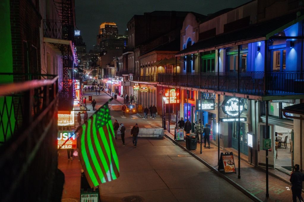 DHS announces New Orleans as latest city swept in immigration crackdown 2 Bourbon Street at night with pedestrians, neon signs, and a green-lit American flag.